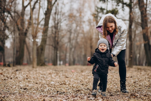 Madre con hijo pequeño juntos en el parque de otoño