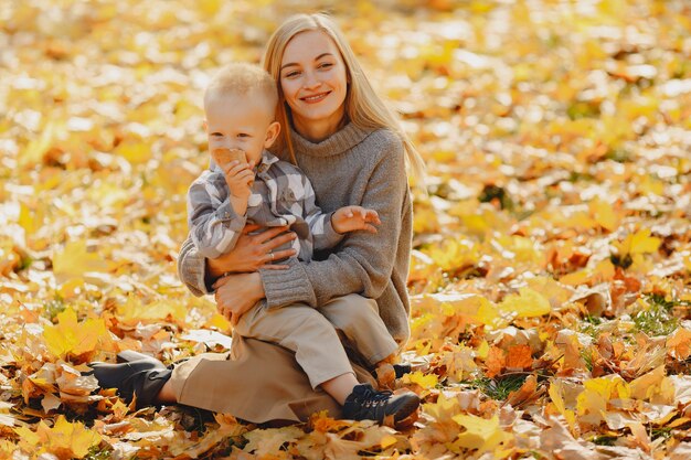 Madre con hijo pequeño sentado en un campo de otoño