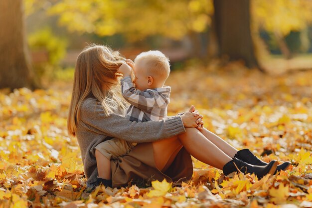 Madre con hijo pequeño sentado en un campo de otoño