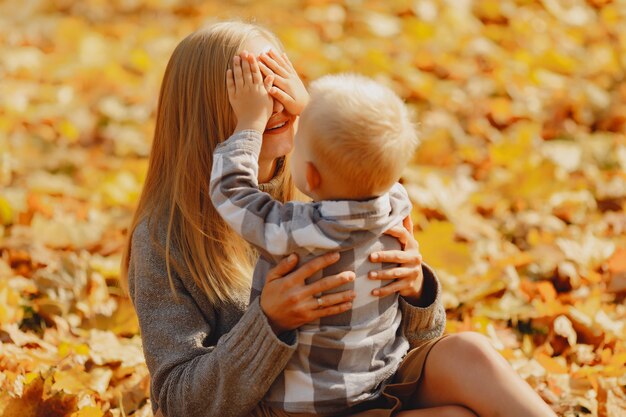 Madre con hijo pequeño sentado en un campo de otoño