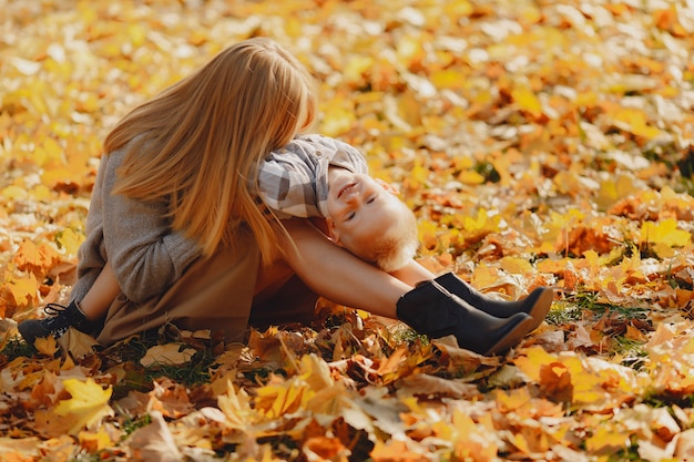 Madre con hijo pequeño sentado en un campo de otoño