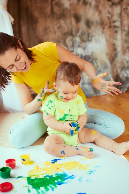 La madre con hijo pintando un papel grande con las manos