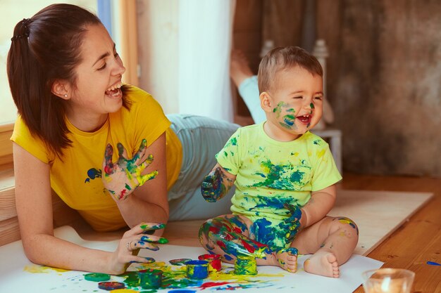 La madre con hijo pintando un papel grande con sus manos