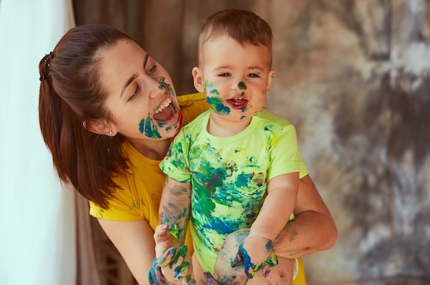 La madre con hijo pintando un papel grande con sus manos