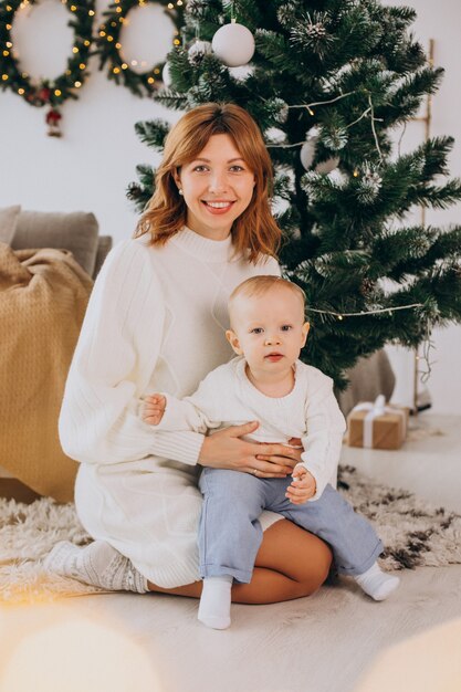 Madre con hijo sentado bajo el árbol de Navidad