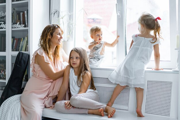 Madre con hijos en un ambiente hogareño. niños por la ventana