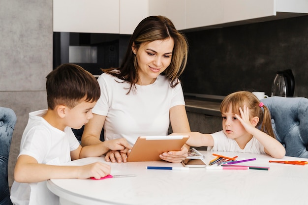 Madre con hijos aprendiendo en casa desde tableta digital