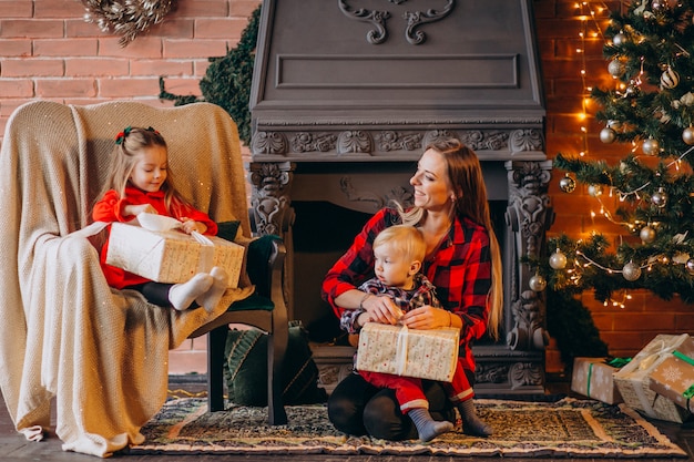 Madre con hijos por arbol de navidad.