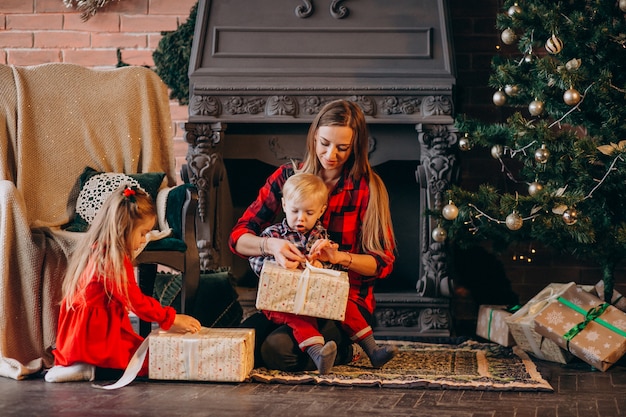 Madre con hijos por arbol de navidad.