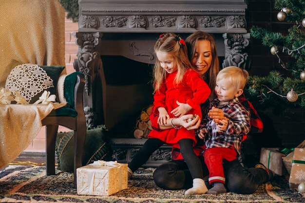 Madre con hijos por arbol de navidad.