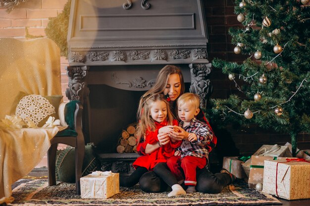 Madre con hijos por arbol de navidad.