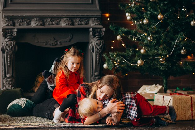 Madre con hijos por arbol de navidad.