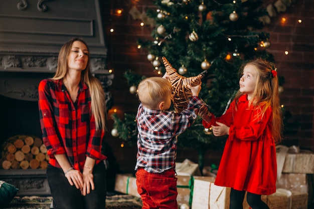 Madre con hijos por arbol de navidad.