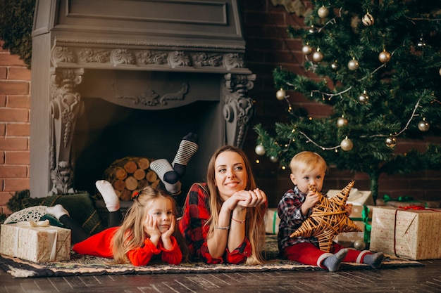 Madre con hijos por arbol de navidad.