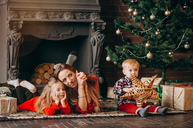 Madre con hijos por arbol de navidad.