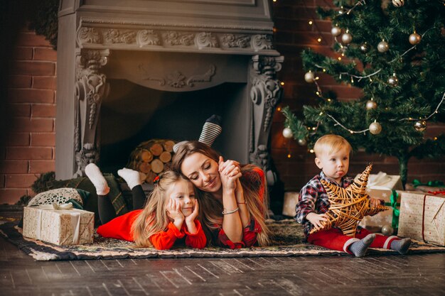 Madre con hijos por arbol de navidad.