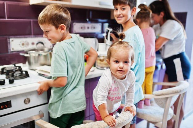 Madre con hijos cocinando en la cocina momentos infantiles felices