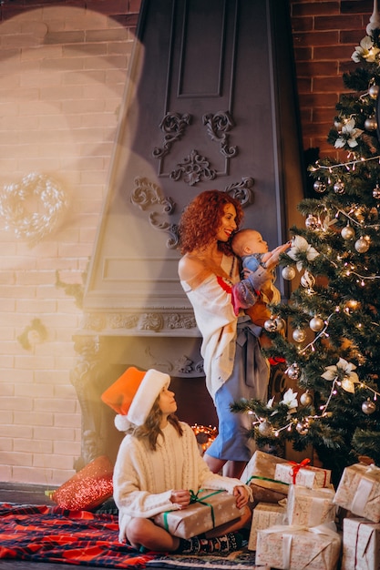 Madre con hijos decorando arbol de navidad