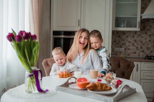 Madre con hijos desayunando en la cocina