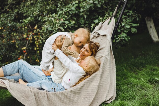 Madre con hijos divirtiéndose en una hamaca. Mamá e hijos en una hamaca.