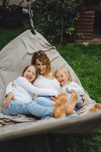 Madre con hijos divirtiéndose en una hamaca. Mamá e hijos en una hamaca.