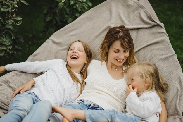 Madre con hijos divirtiéndose en una hamaca. Mamá e hijos en una hamaca.