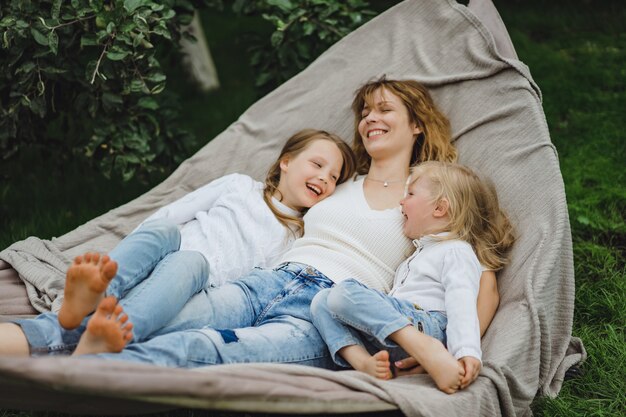 Madre con hijos divirtiéndose en una hamaca. Mamá e hijos en una hamaca.