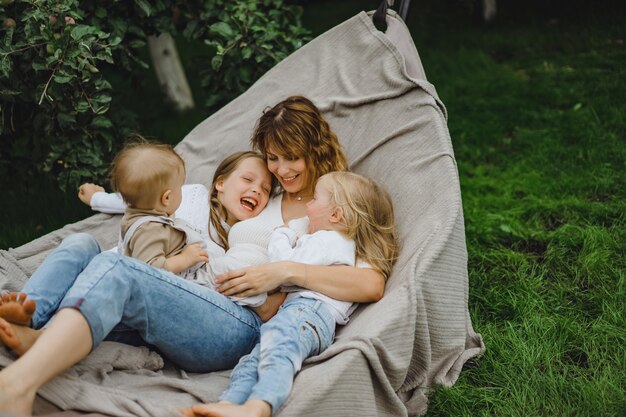 Madre con hijos divirtiéndose en una hamaca. Mamá e hijos en una hamaca.