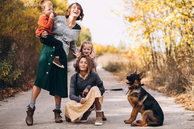 Madre con hijos y perro en un parque de otoño