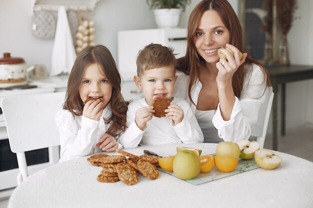 Madre con hijos sentados en la cocina y comer