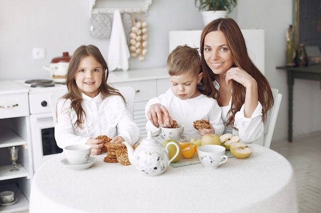 Madre con hijos sentados en la cocina y comer