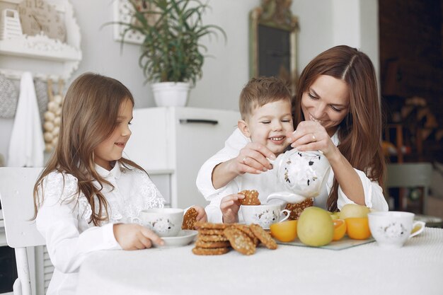 Madre con hijos sentados en la cocina y comer