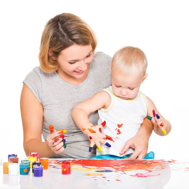 Madre joven feliz con una pintura de bebé con las manos aisladas en blanco.