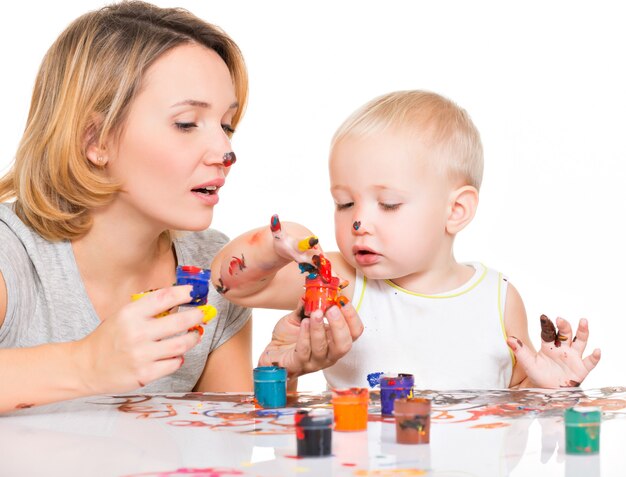 Madre joven feliz con una pintura de niño con las manos aisladas en blanco.