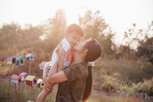 Madre joven feliz que juega y que se divierte con su pequeño hijo del bebé en el parque en un día de verano soleado