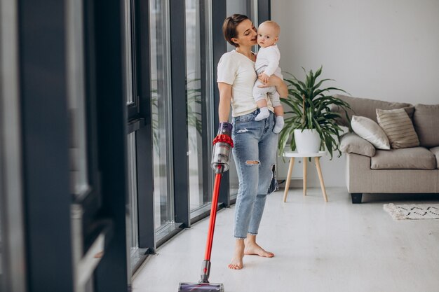 Madre joven con hijo pequeño limpiando en casa