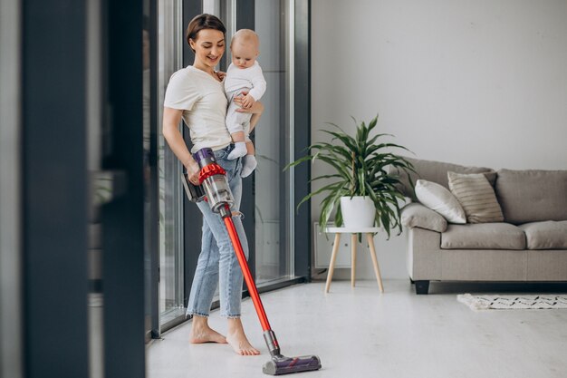 Madre joven con hijo pequeño limpiando en casa