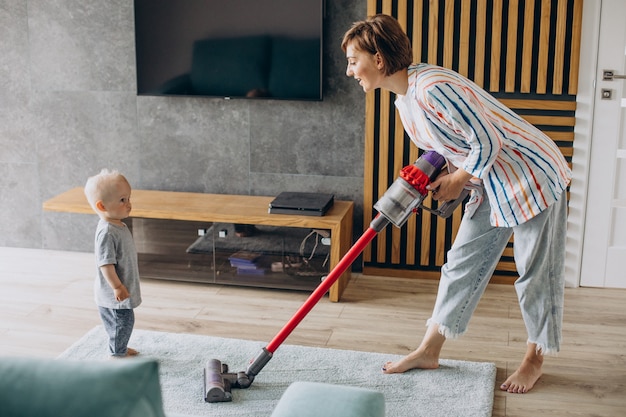 Foto gratuita madre joven con hijo pequeño limpiando en casa