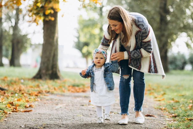 Madre joven con su pequeña hija en un parque del otoño