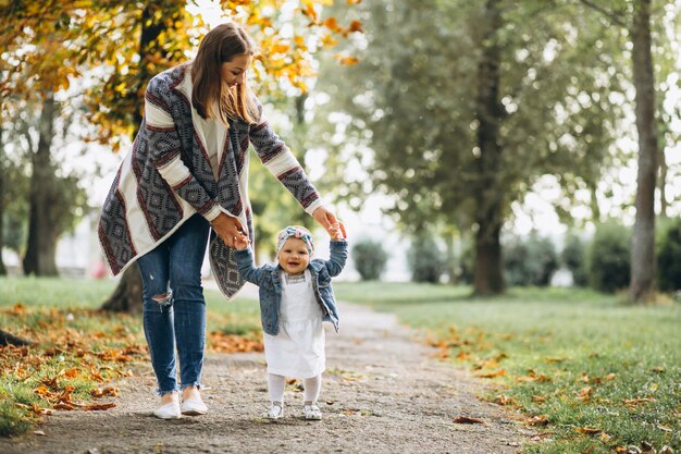 Madre joven con su pequeña hija en un parque del otoño