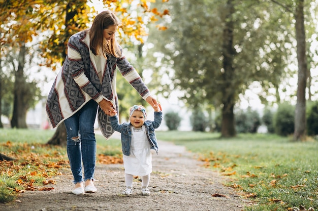 Madre joven con su pequeña hija en un parque del otoño