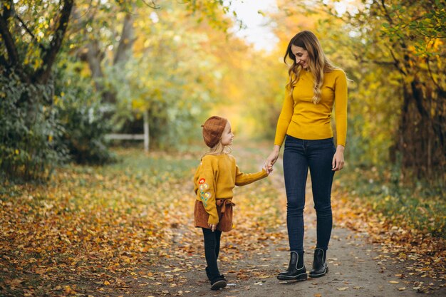 Madre joven con su pequeña hija en un parque del otoño