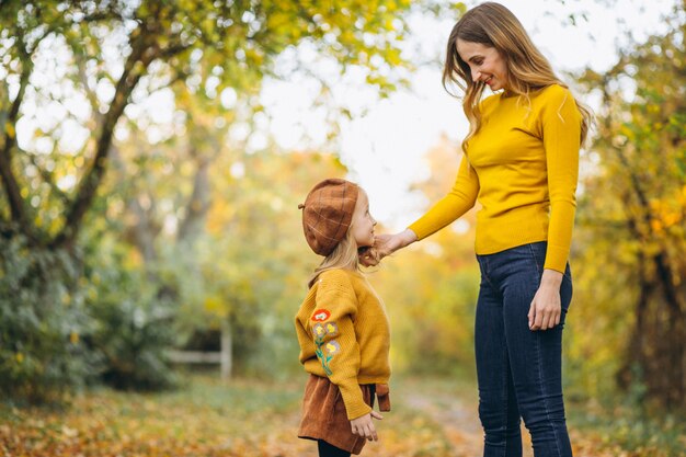 Madre joven con su pequeña hija en un parque del otoño