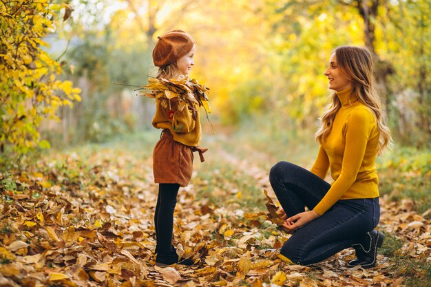 Madre joven con su pequeña hija en un parque del otoño