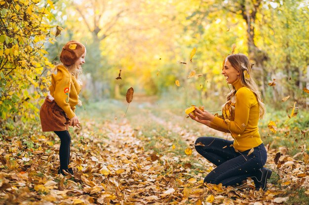 Madre joven con su pequeña hija en un parque del otoño