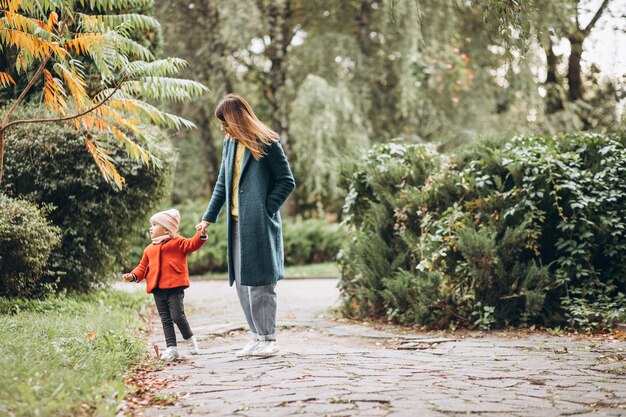 Madre joven con su pequeña hija en un parque de otoño