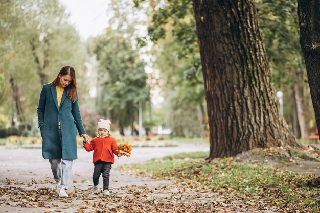 Madre joven con su pequeña hija en un parque de otoño