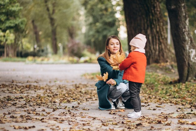 Madre joven con su pequeña hija en un parque de otoño