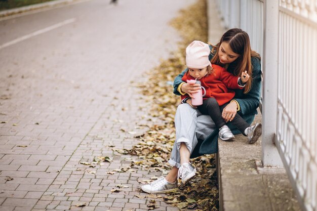 Madre joven con su pequeña hija en un parque de otoño