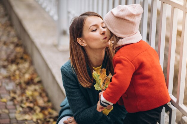 Madre joven con su pequeña hija en un parque de otoño